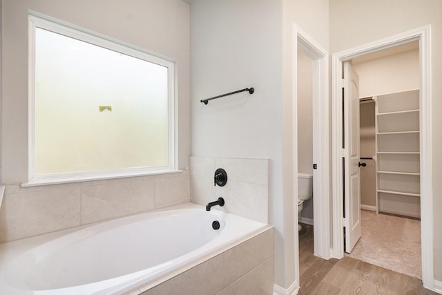 bathroom featuring hardwood / wood-style floors, toilet, and tiled tub