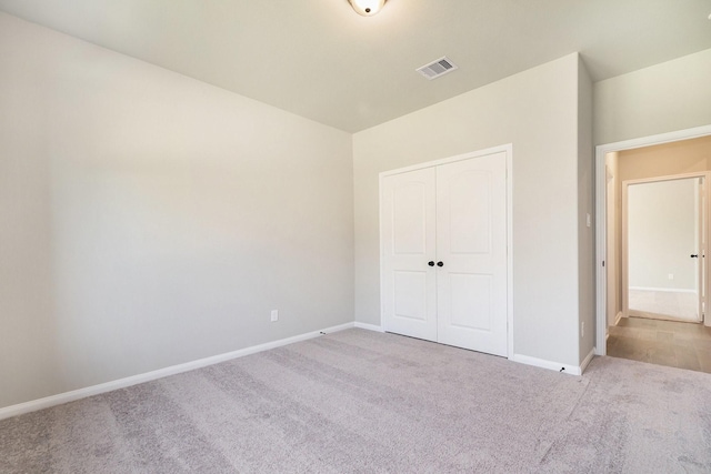 unfurnished bedroom featuring light colored carpet and a closet