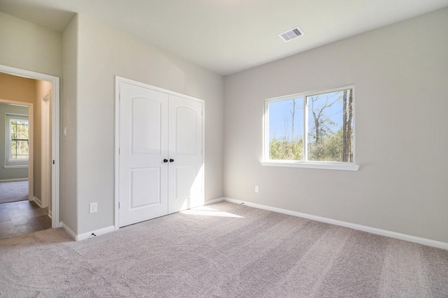 unfurnished bedroom with light carpet and a closet