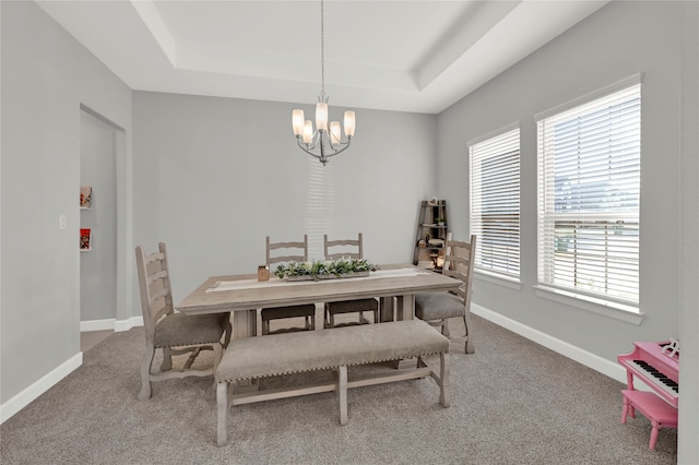 dining area featuring a healthy amount of sunlight, carpet flooring, an inviting chandelier, and a raised ceiling