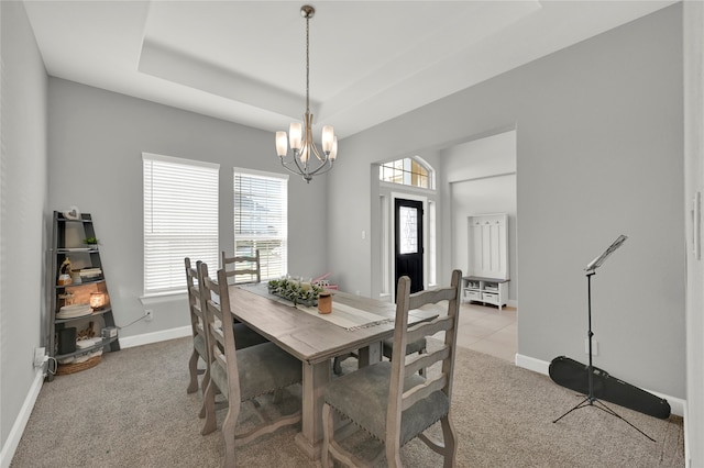 carpeted dining space with a wealth of natural light, a notable chandelier, and a raised ceiling