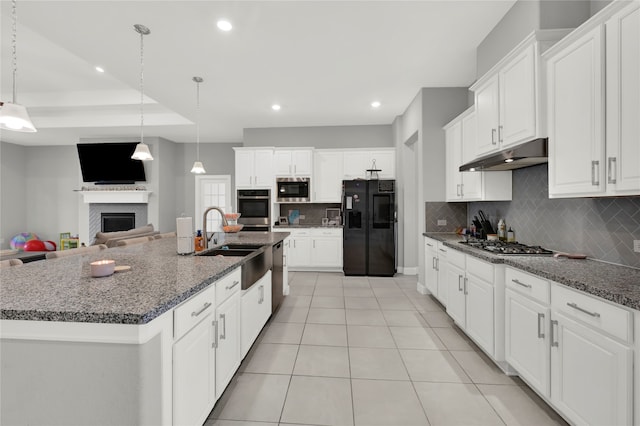 kitchen featuring a kitchen island with sink, stainless steel appliances, sink, pendant lighting, and white cabinetry