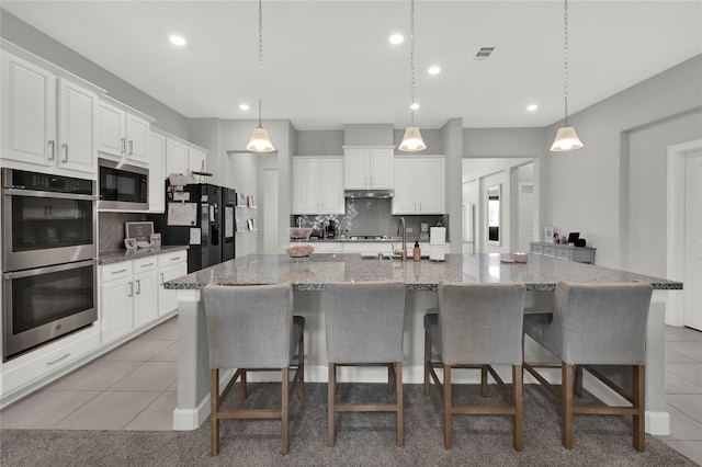 kitchen featuring hanging light fixtures, stainless steel appliances, a large island, light tile patterned floors, and white cabinetry