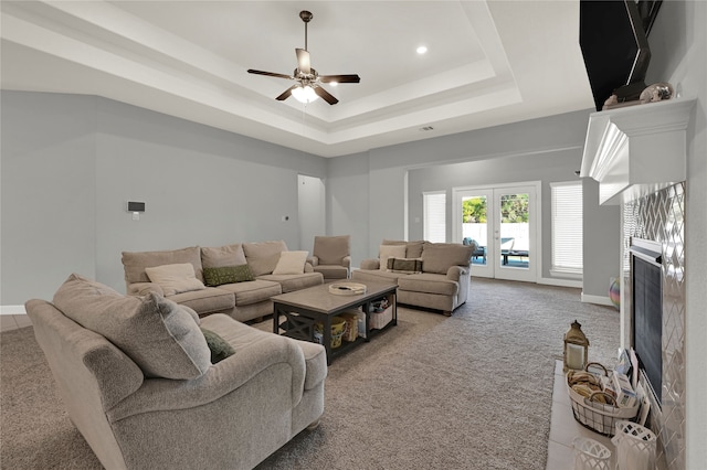 carpeted living room with french doors, ceiling fan, and a raised ceiling