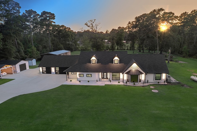 back house at dusk featuring an outbuilding, a yard, and a garage