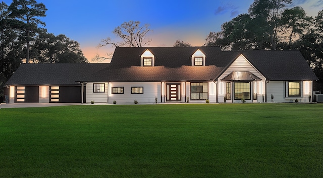 view of front of property featuring a yard, cooling unit, and a garage