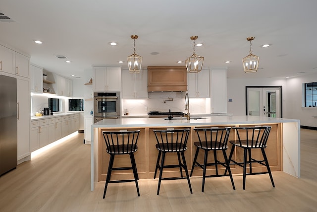 kitchen featuring a spacious island, light hardwood / wood-style floors, and white cabinets