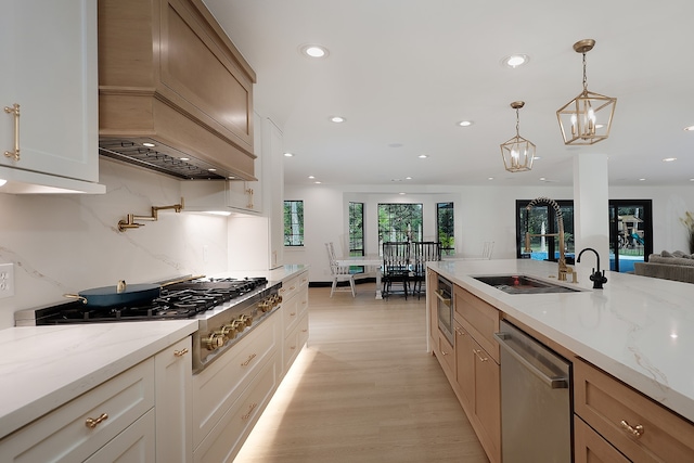 kitchen featuring light hardwood / wood-style flooring, stainless steel appliances, sink, pendant lighting, and custom exhaust hood