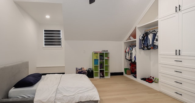 bedroom featuring a closet, ornamental molding, vaulted ceiling, and light wood-type flooring