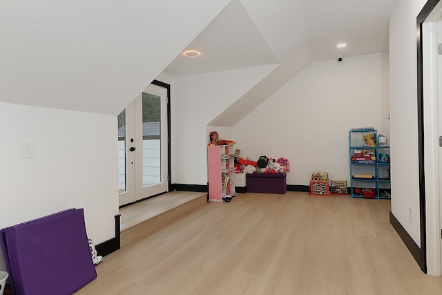 rec room with french doors, vaulted ceiling, and light hardwood / wood-style floors