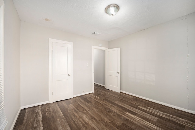 unfurnished room featuring dark hardwood / wood-style floors and a textured ceiling