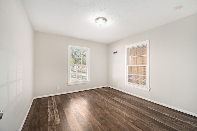 empty room with a textured ceiling and dark hardwood / wood-style floors