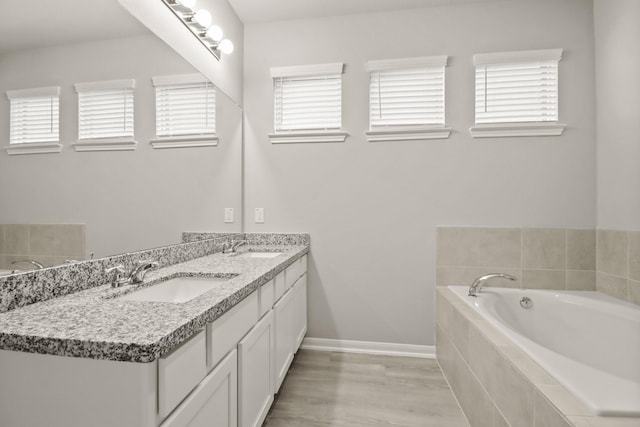 bathroom with vanity, tiled bath, and a healthy amount of sunlight