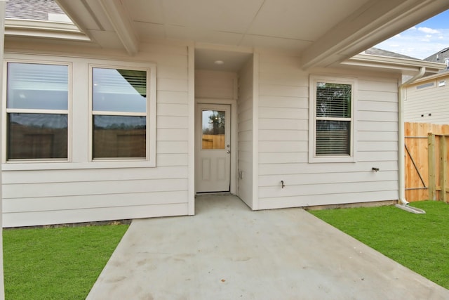 view of exterior entry with a yard and a patio