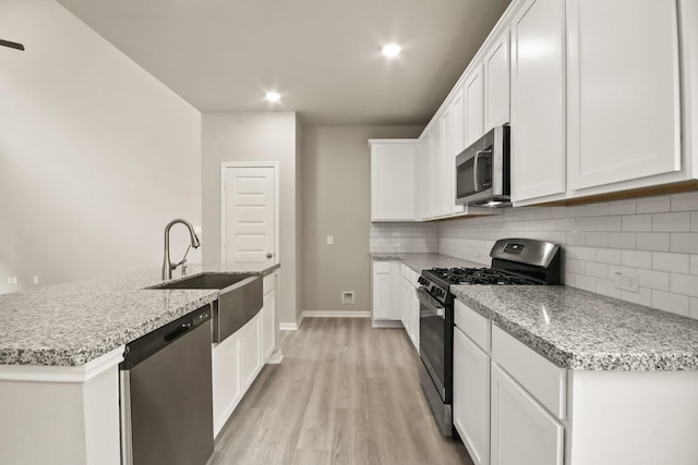 kitchen featuring white cabinetry, sink, stainless steel appliances, and an island with sink