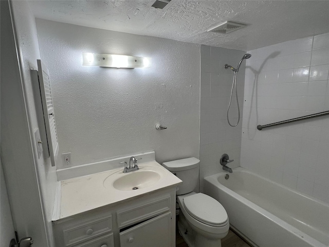 full bathroom with a textured ceiling, vanity, tiled shower / bath combo, and toilet