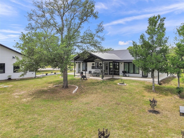 back of house featuring a yard, a patio, a fire pit, and metal roof