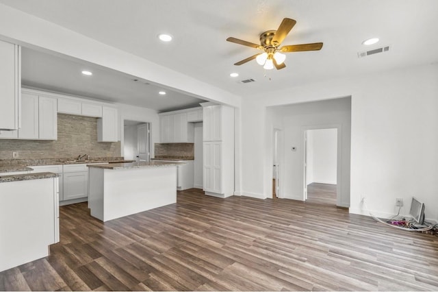 kitchen featuring a center island, hardwood / wood-style floors, tasteful backsplash, ceiling fan, and white cabinetry