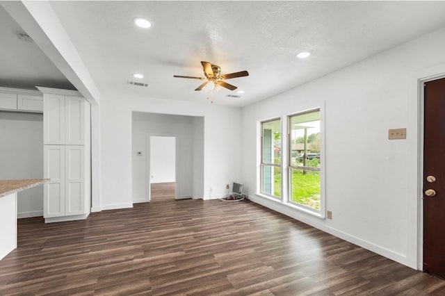 unfurnished living room with dark hardwood / wood-style flooring, a textured ceiling, and ceiling fan