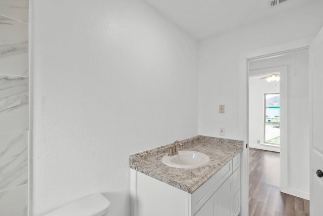 bathroom featuring wood-type flooring, ceiling fan, toilet, and vanity