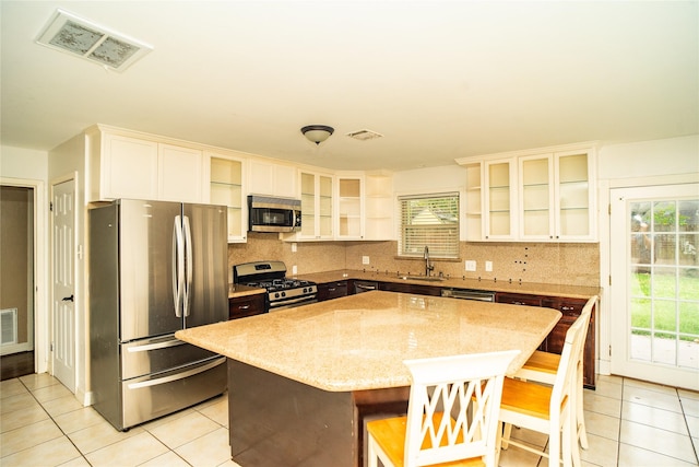 kitchen featuring a center island, stainless steel appliances, a healthy amount of sunlight, and a breakfast bar area