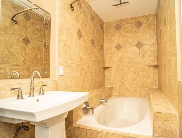 bathroom with tiled shower / bath combo, sink, and tile walls