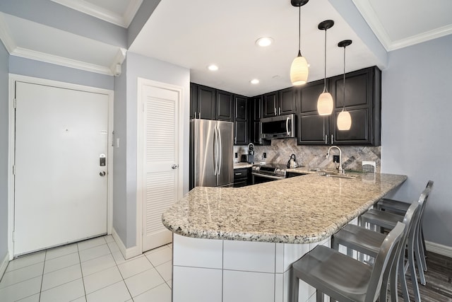 kitchen featuring sink, kitchen peninsula, decorative light fixtures, decorative backsplash, and appliances with stainless steel finishes