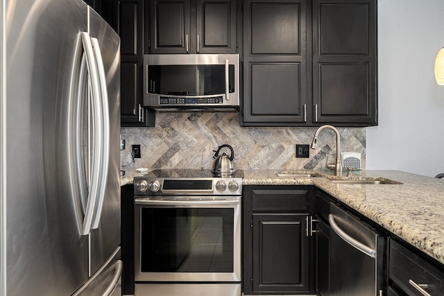 kitchen featuring tasteful backsplash, light stone counters, sink, and stainless steel appliances