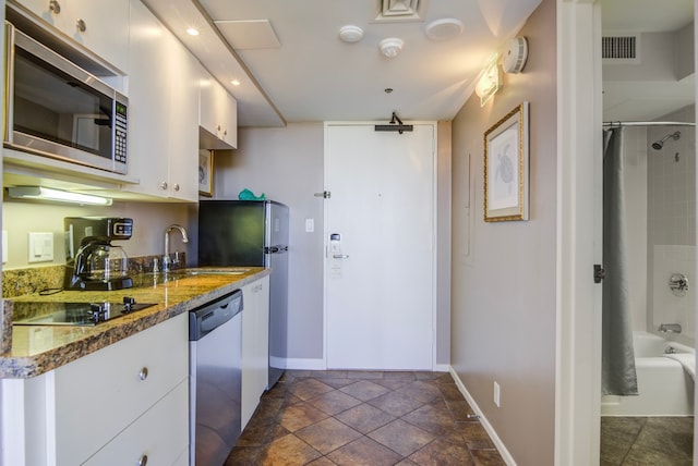 kitchen with sink, appliances with stainless steel finishes, dark stone counters, and white cabinets