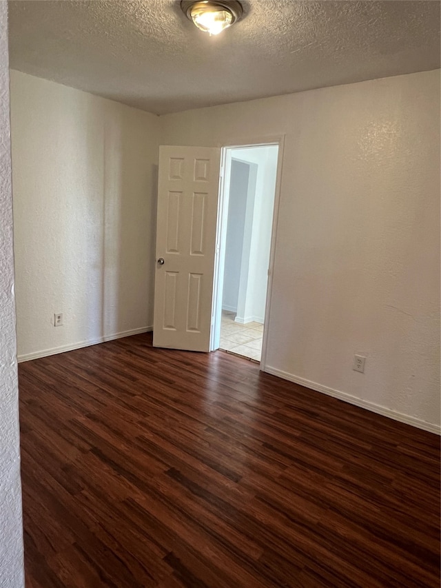 spare room featuring a textured ceiling and dark hardwood / wood-style flooring