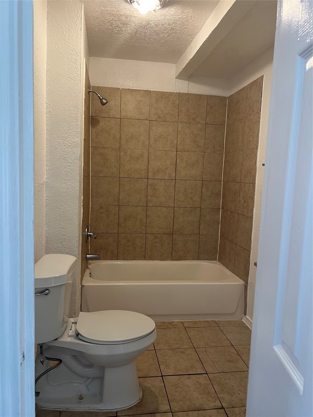 bathroom with toilet, tiled shower / bath combo, a textured ceiling, and tile patterned flooring