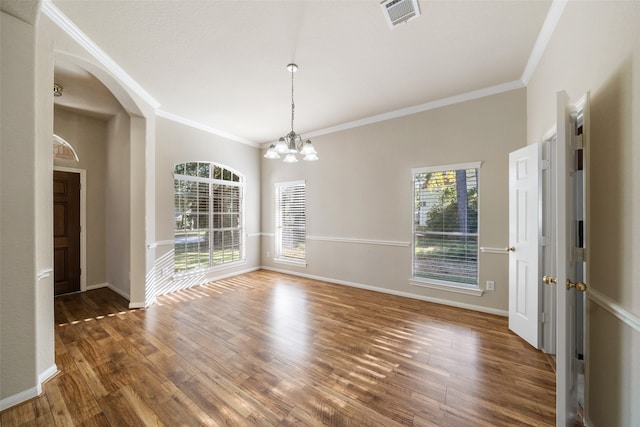 unfurnished dining area with an inviting chandelier, ornamental molding, plenty of natural light, and dark hardwood / wood-style flooring