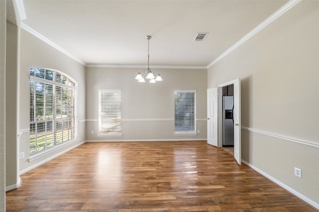 unfurnished dining area featuring crown molding, hardwood / wood-style floors, and a chandelier