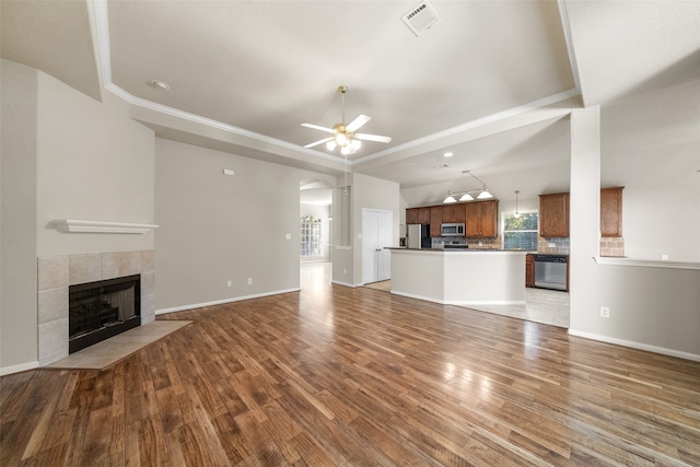 unfurnished living room with a wealth of natural light, a fireplace, hardwood / wood-style flooring, and ceiling fan