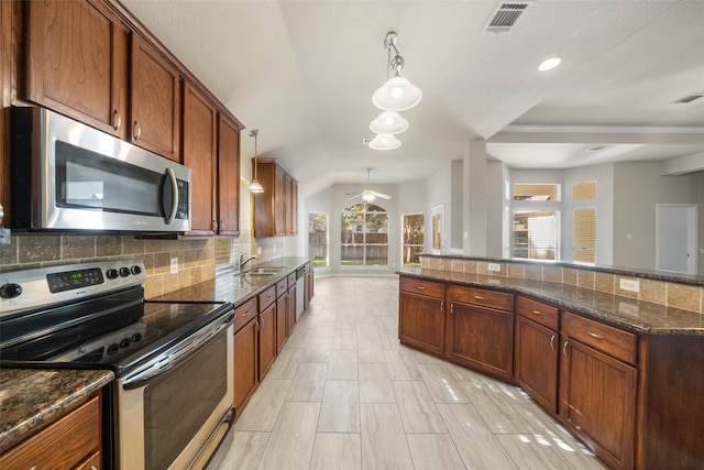 kitchen featuring decorative backsplash, dark stone countertops, stainless steel appliances, and pendant lighting