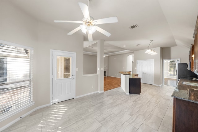 kitchen featuring ceiling fan, stainless steel refrigerator, vaulted ceiling, sink, and decorative light fixtures