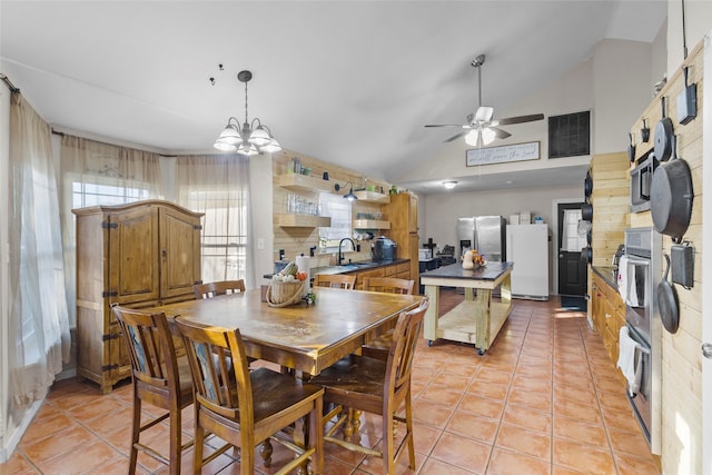 tiled dining area featuring sink, lofted ceiling, and ceiling fan with notable chandelier