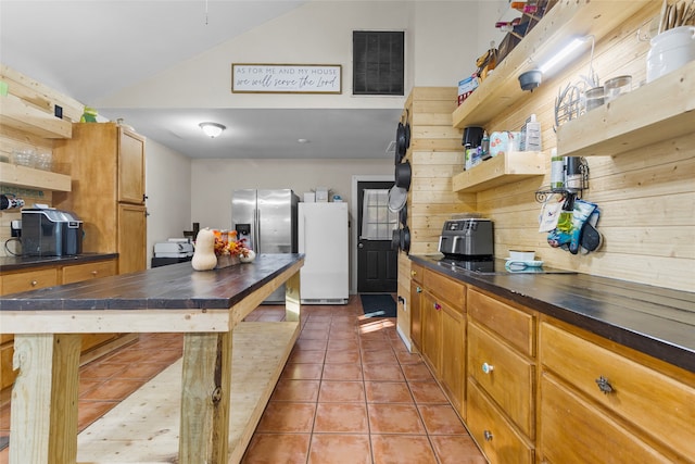 kitchen featuring lofted ceiling, decorative backsplash, light tile patterned floors, stainless steel refrigerator with ice dispenser, and white refrigerator