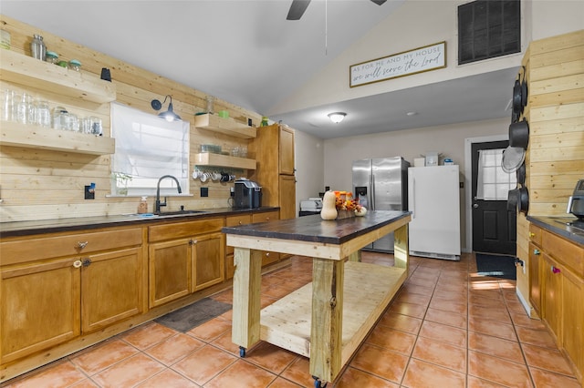 kitchen with light tile patterned floors, stainless steel fridge with ice dispenser, vaulted ceiling, white fridge, and sink