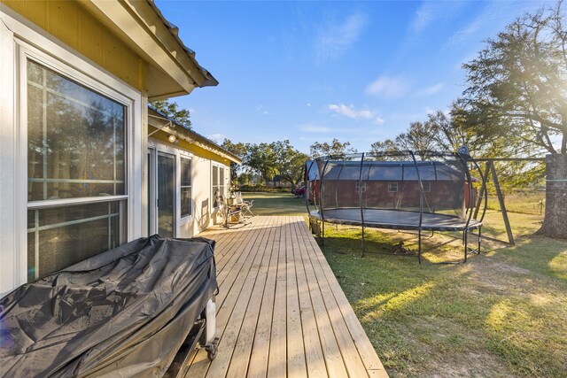 wooden deck featuring a yard and a trampoline