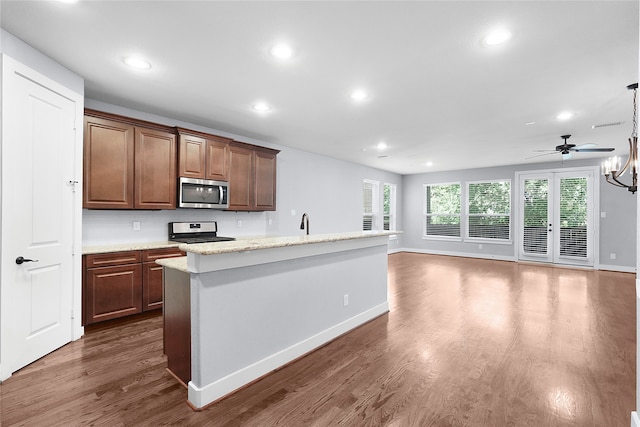 kitchen featuring stove, a center island with sink, dark hardwood / wood-style floors, ceiling fan, and decorative light fixtures