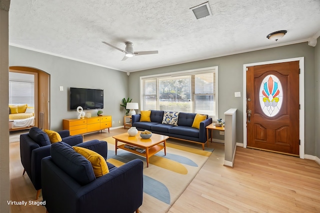 living room with ceiling fan, ornamental molding, a textured ceiling, and light hardwood / wood-style flooring