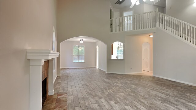 5802 Sugar Bush Dr, Magnolia, TX 77354 - unfurnished living room with a ceiling fan, a high ceiling, arched walkways, and wood finished floors