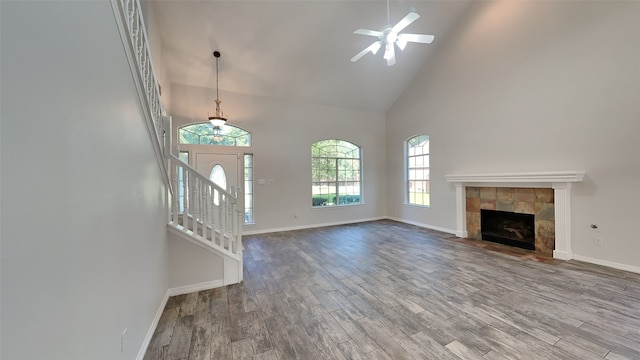 unfurnished living room featuring hardwood / wood-style flooring, high vaulted ceiling, a fireplace, and ceiling fan