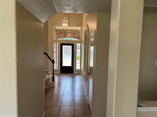 tiled entrance foyer with lofted ceiling and a notable chandelier