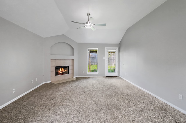 unfurnished living room featuring lofted ceiling, a tiled fireplace, carpet flooring, and ceiling fan