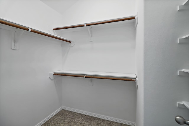 walk in closet with dark colored carpet