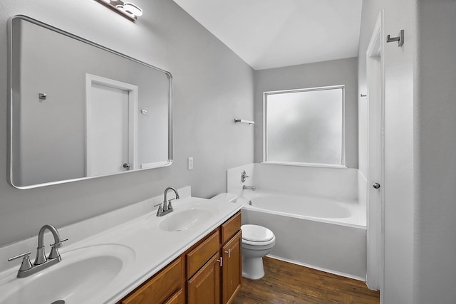 bathroom with vanity, toilet, hardwood / wood-style flooring, and a tub to relax in