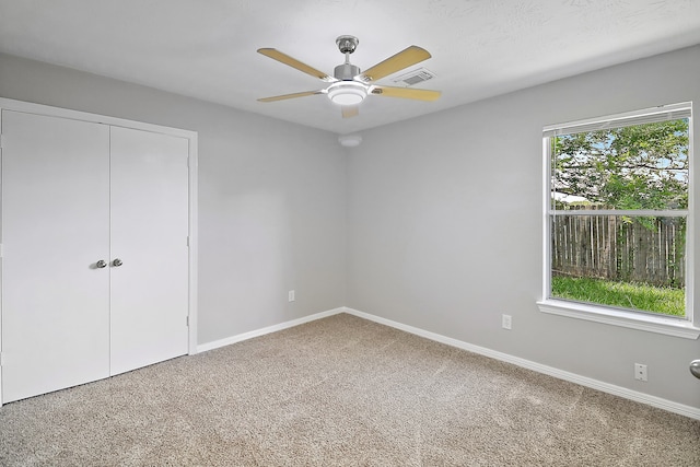 unfurnished bedroom featuring ceiling fan, multiple windows, and carpet floors