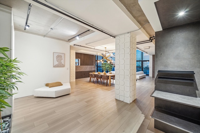 staircase with a chandelier, wood-type flooring, and decorative columns